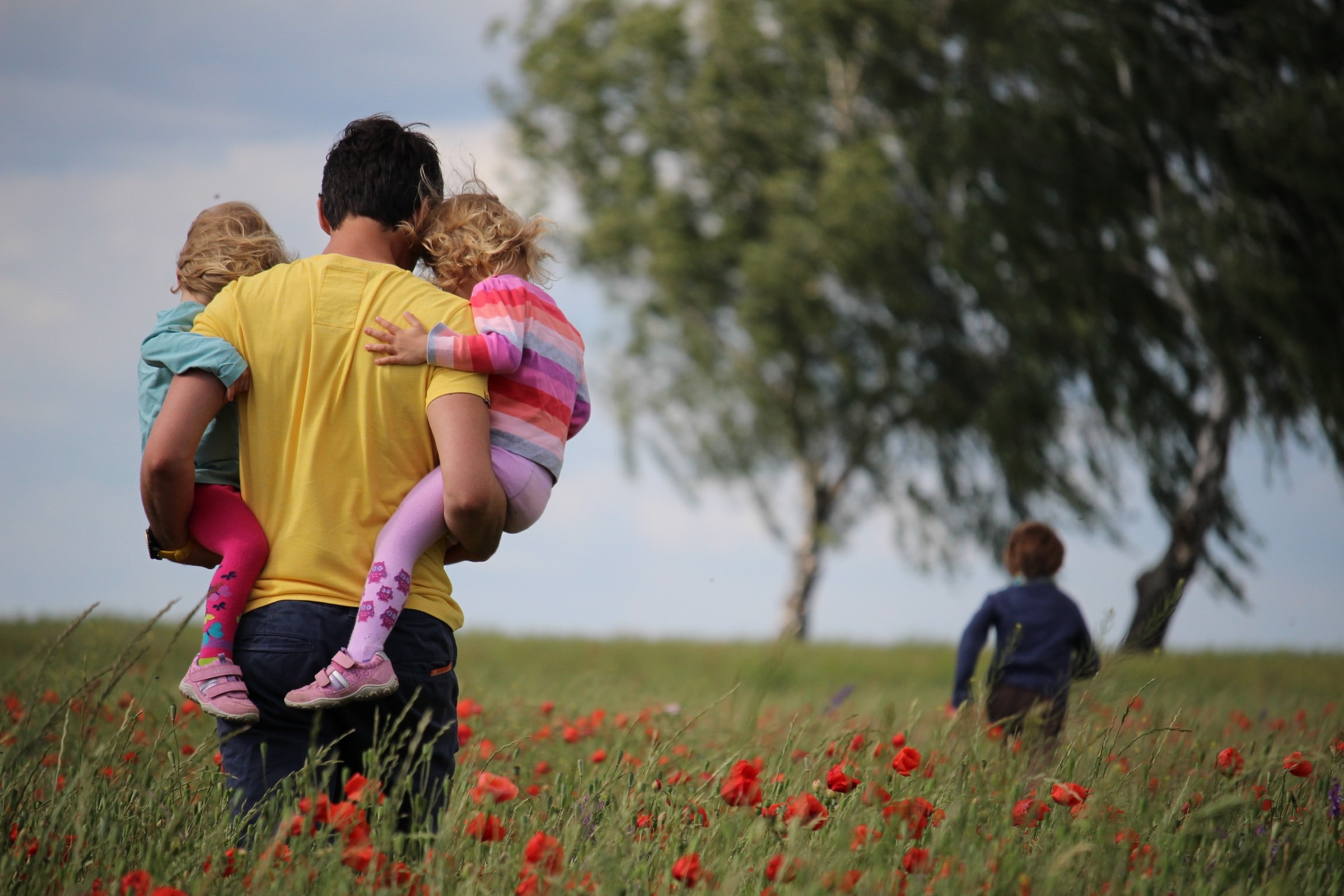 benefits of having life insurance. Man in a field holding 3 children