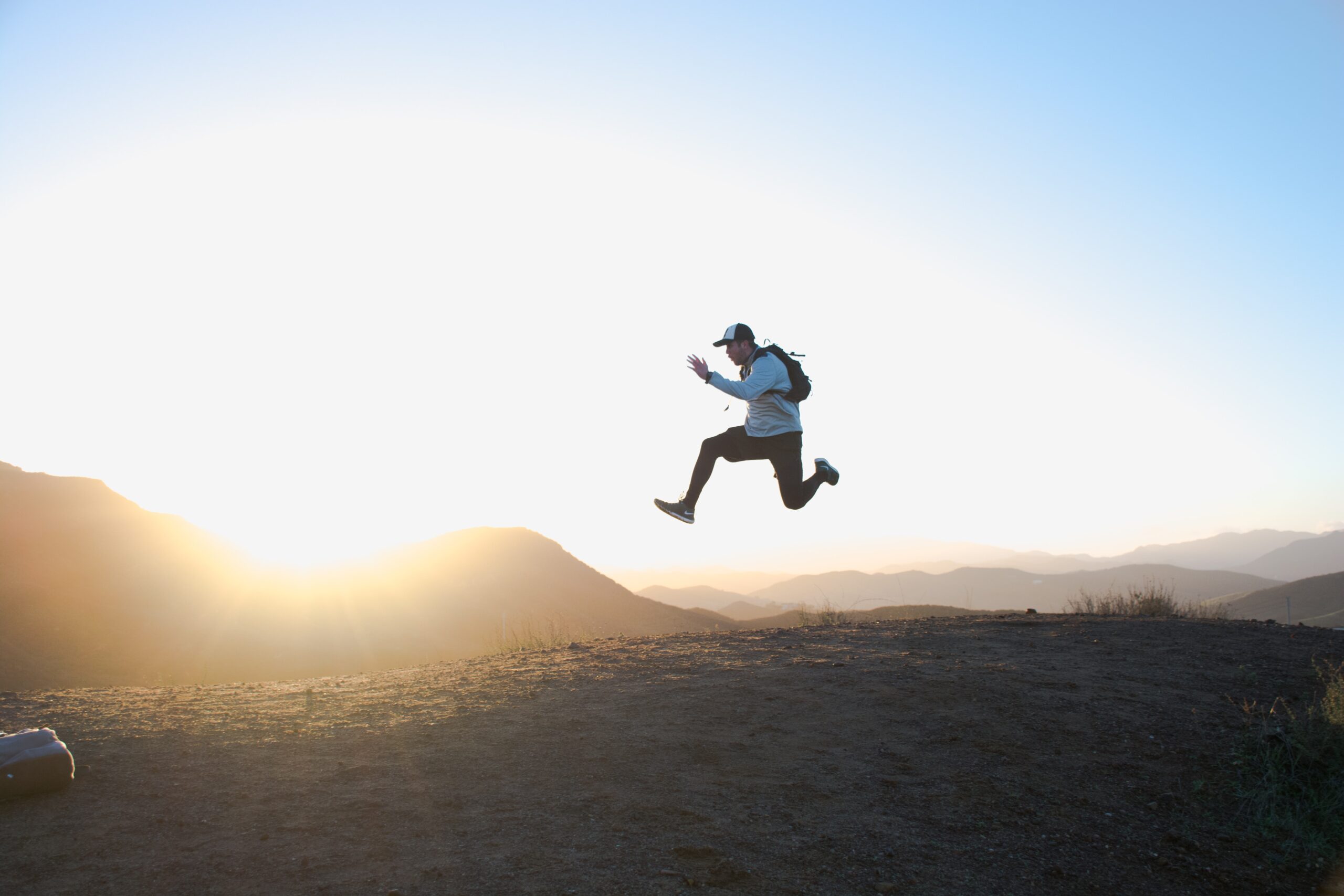 man jumping in the air in front of a sunset