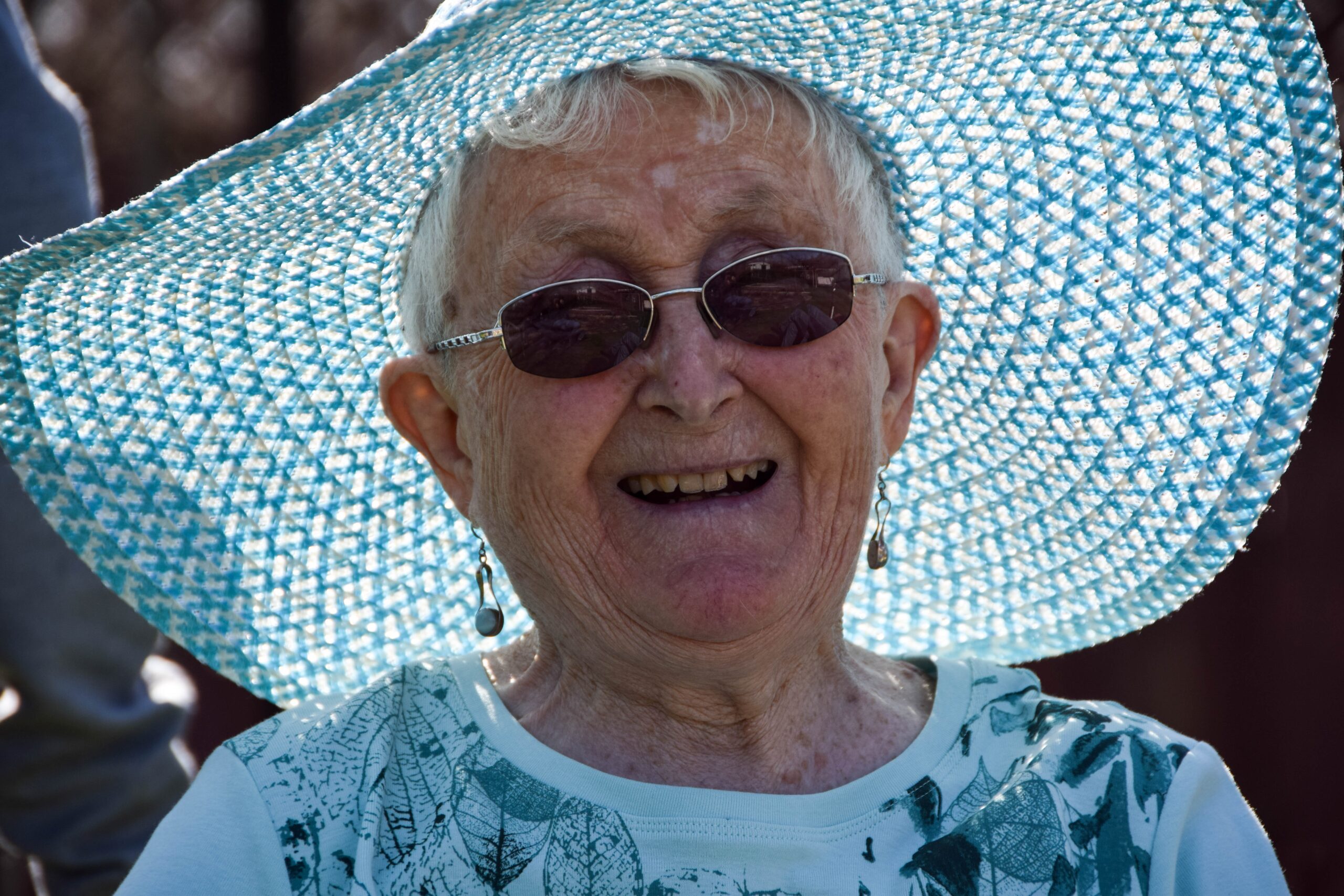 elderly woman smiling and wearing a hat