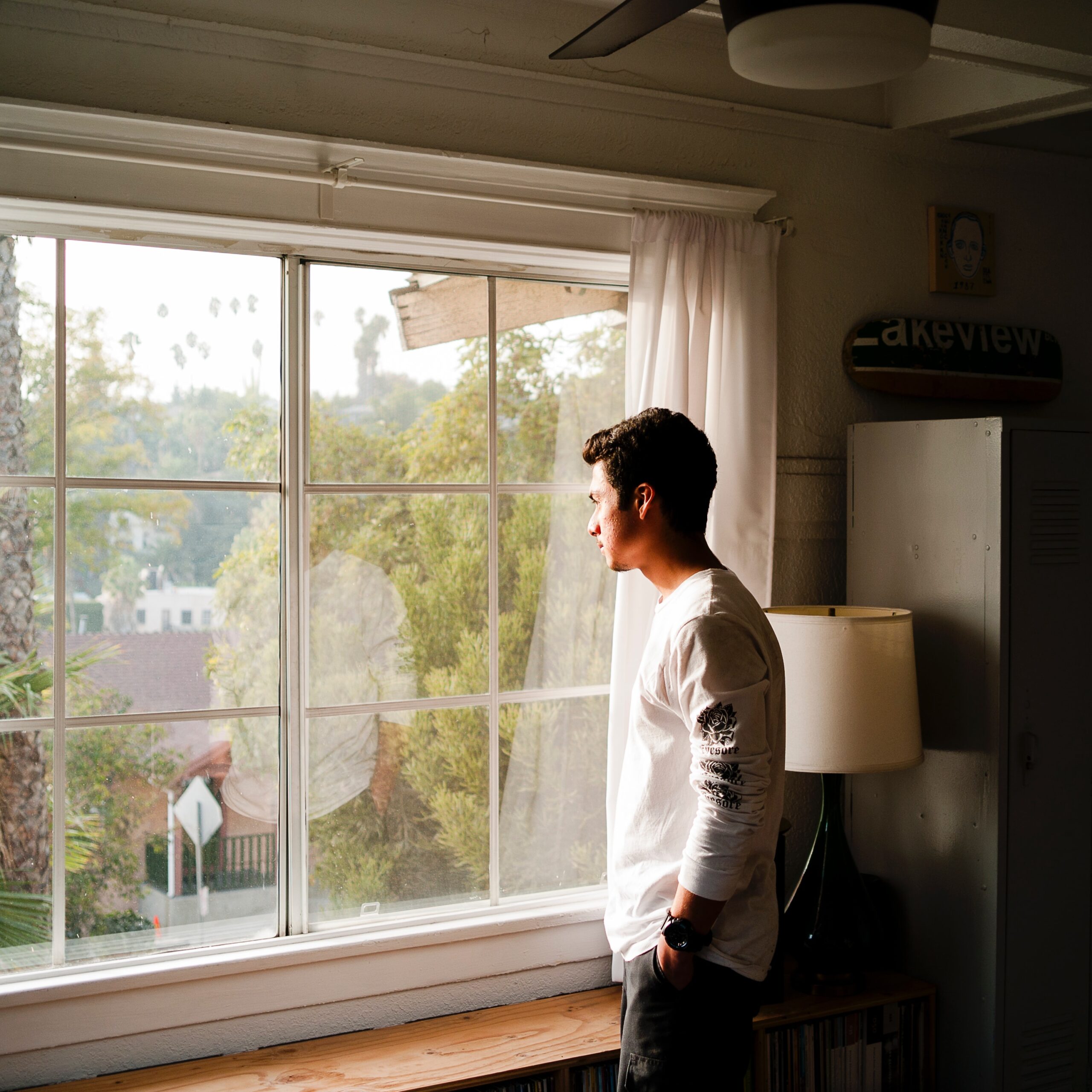 man standing at window, looking outside